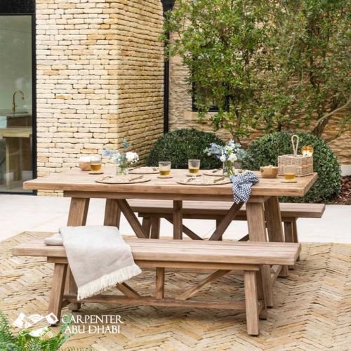 Rustic outdoor dining setup with wooden table, benches, and cozy decorations.